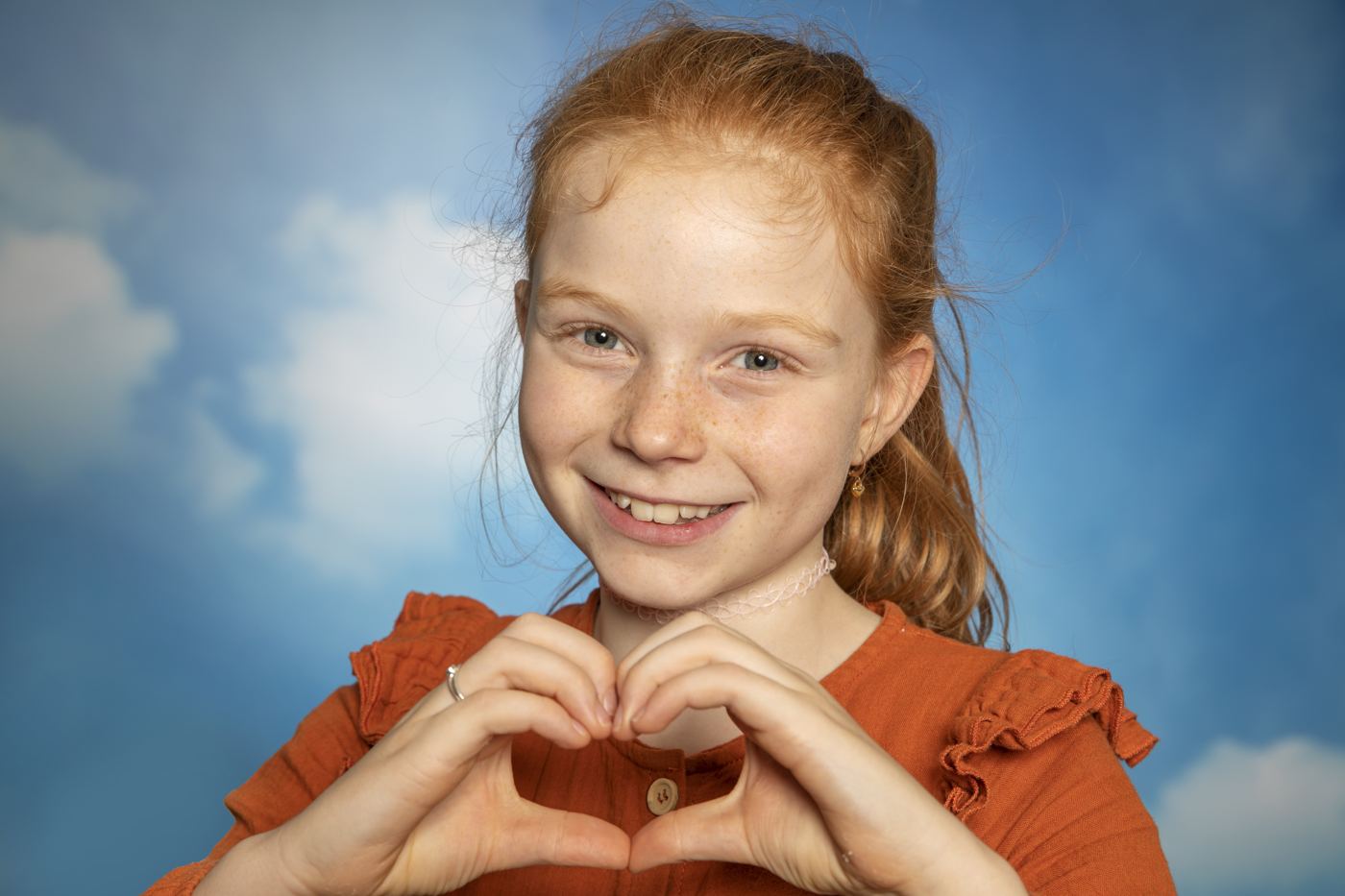 Een meisje maakt een hartje met haar handen